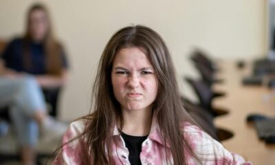 An angry teenage girl sitting in a classroom, displaying a frustrated expression.