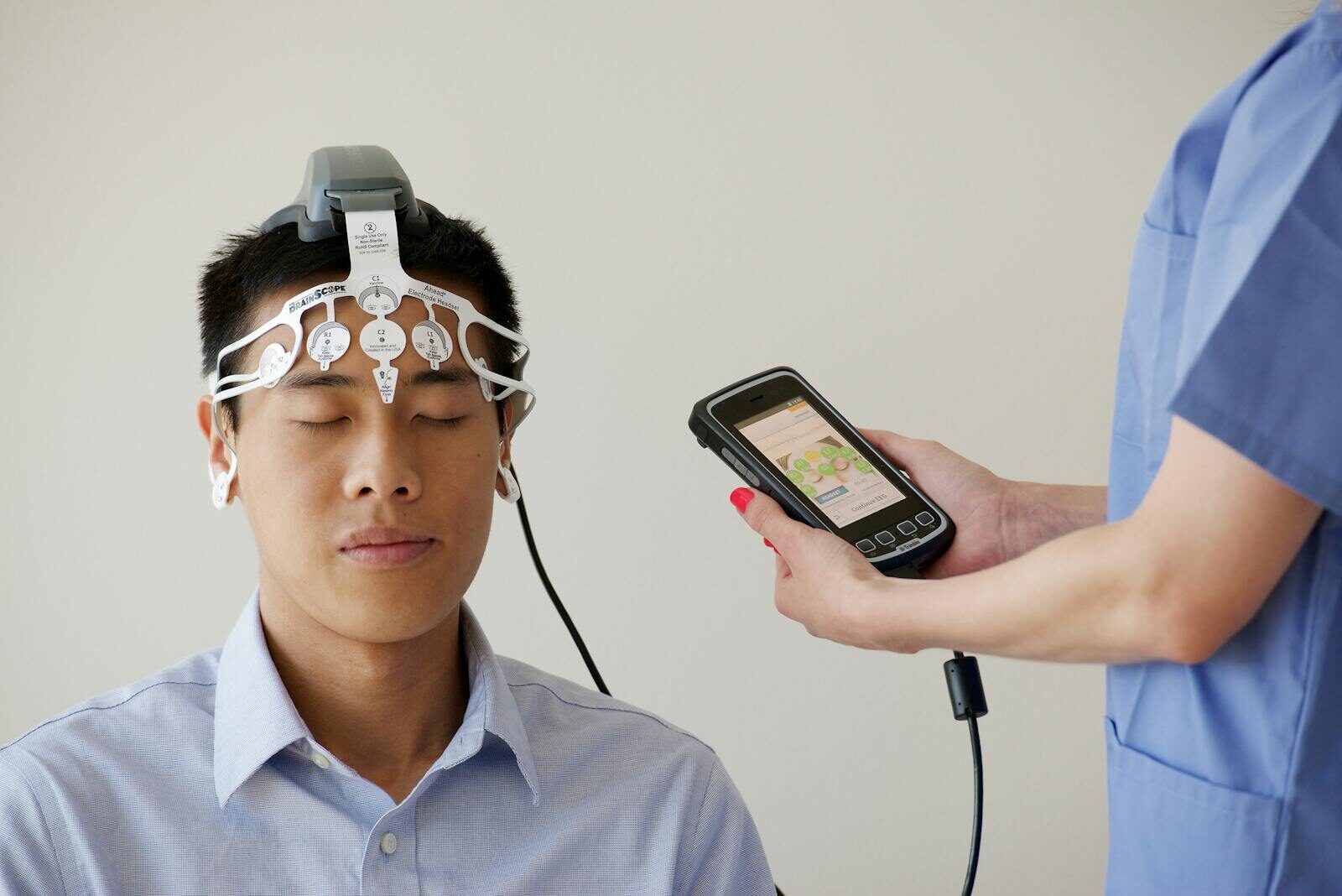 Healthcare professional conducting an EEG examination using a Brainscope device on a male patient.