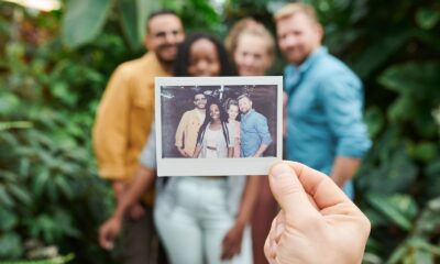 A group of friends enjoying a moment with an instant camera photo surrounded by lush greenery.