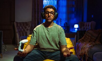 Young man gaming indoors at night, focused on the screen, wearing headphones and holding a controller.