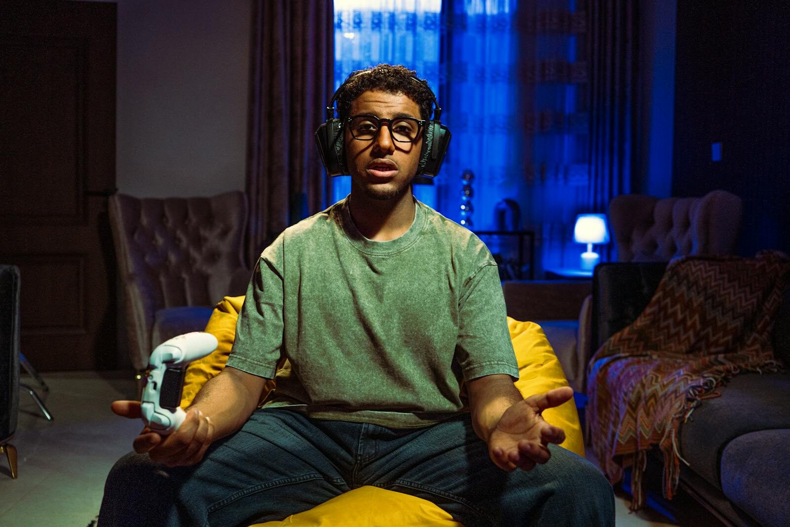 Young man gaming indoors at night, focused on the screen, wearing headphones and holding a controller.