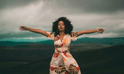 A woman in a flowing dress enjoys peaceful moments in a vast, cloudy landscape.