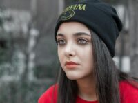A contemplative young woman in a beanie, captured with a moody tone.