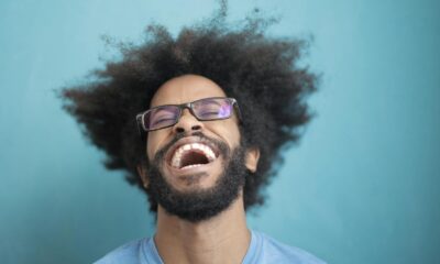Portrait of a joyful man laughing with an afro hairstyle against a blue background.