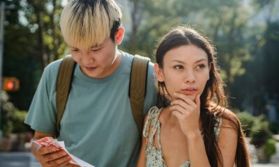 Confused multiracial couple searching way in map while discovering city together during summer holidays