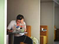 Man showing stress and frustration while working remotely on a laptop indoors.
