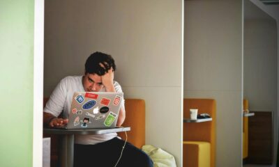 Man showing stress and frustration while working remotely on a laptop indoors.