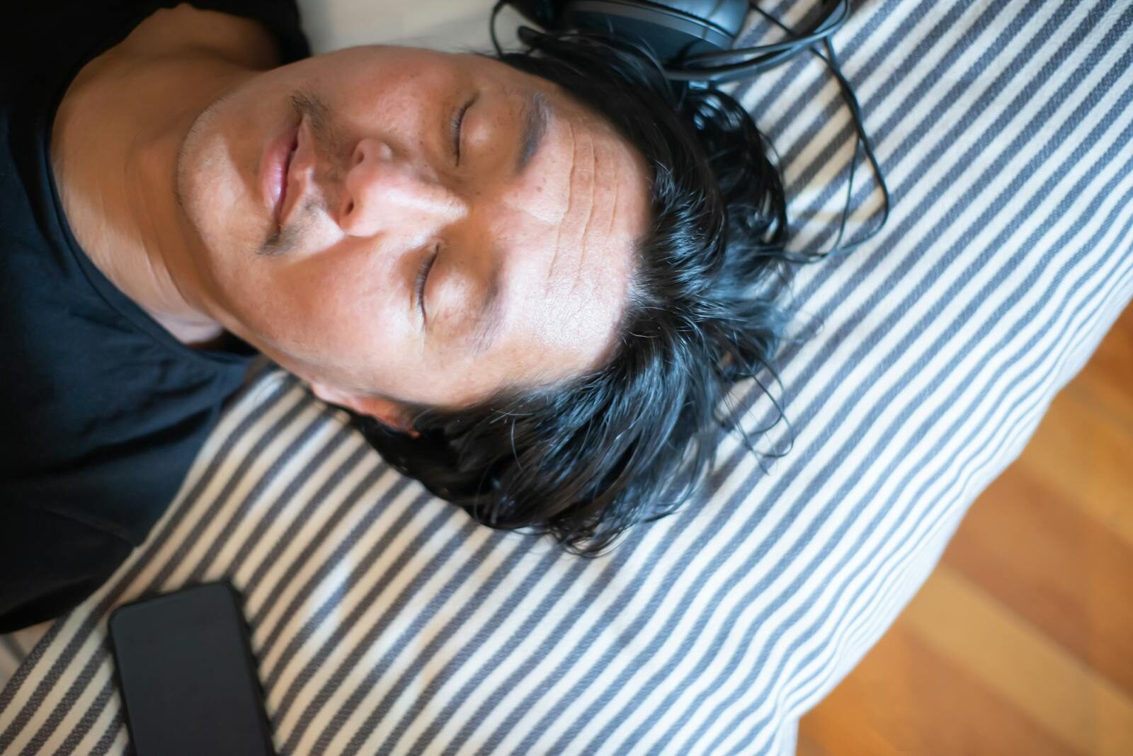 Close-up of a man relaxing with closed eyes and headphones, epitomizing tranquility.