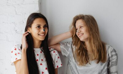 Two happy teen girls smiling together, enjoying a moment indoors. Perfect for friendship and lifestyle themes.