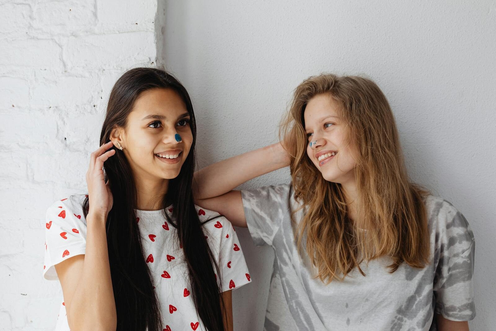 Two happy teen girls smiling together, enjoying a moment indoors. Perfect for friendship and lifestyle themes.