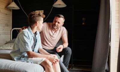 A father bonding with his teenage son in a cozy bedroom, sharing advice and conversation.